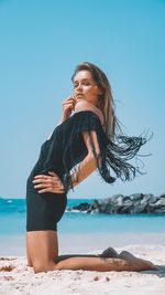 Woman wearing sunglasses at beach against clear sky