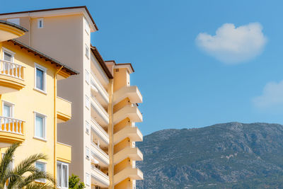 Scenic view of the hill and part of the residential building against the blue sky.