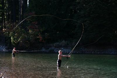 Shirtless brothers fishing in lake