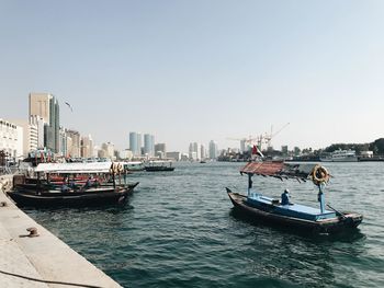 Nautical vessel on sea by buildings against clear sky