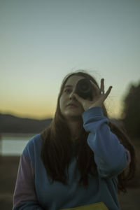 Portrait of young woman wearing sunglasses against sky during sunset