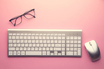 Directly above shot of computer keyboard and mouse by eyeglasses on table