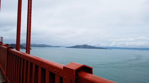 Close-up of railing by sea against sky