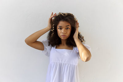 Portrait of young woman standing against white background