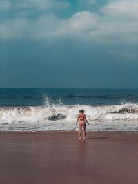 Rear view of shirtless man on beach against sky