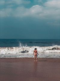 Rear view of shirtless man on beach against sky