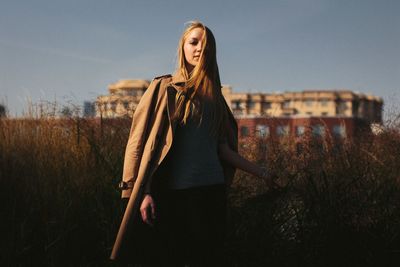 Young woman standing on field against sky