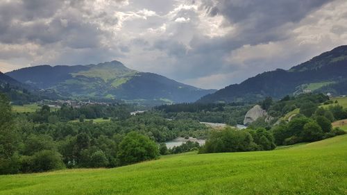 Scenic view of green landscape and mountains against sky