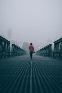 Rear view of man walking on footbridge