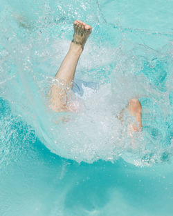 Low section of person with feet up swimming in pool