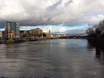 River with buildings in background against cloudy sky