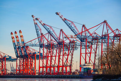 Cranes at commercial dock against sky