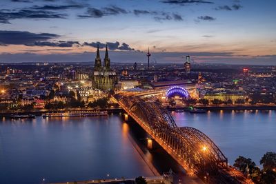 Illuminated bridge over river against sky in city at night