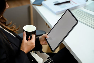 Midsection of woman using laptop at table