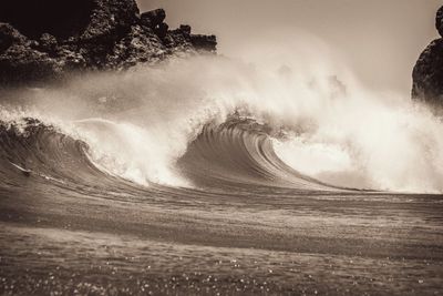 Scenic view of waves breaking on shore against sky