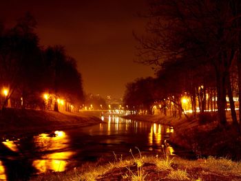 View of canal along trees at night