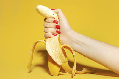 Close-up of woman hand holding yellow over white background