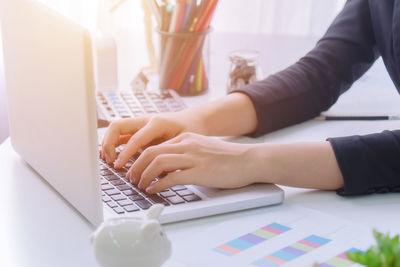 Midsection of woman using laptop on table