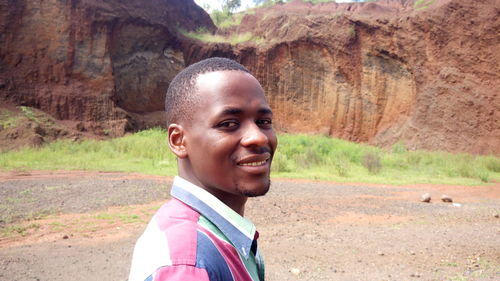 Portrait of smiling young man against cliff