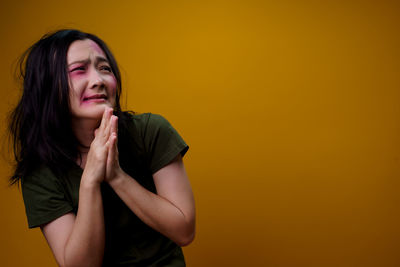 Portrait of beautiful young woman against yellow background