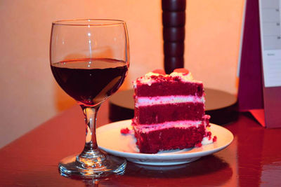 Wine with red velvet cake on table