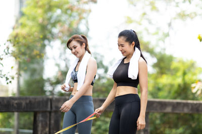 Side view of young woman standing against trees