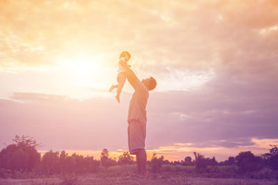 Low angle view of man standing on field against sky during sunset