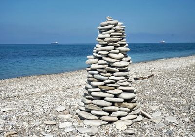 Pebbles on shore against cloudy sky