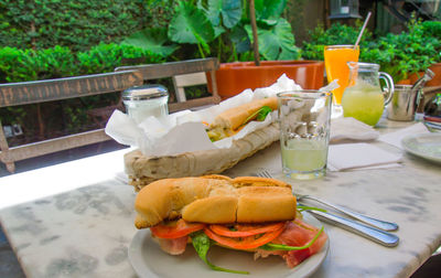 Sandwich and lemonade served on table at yard