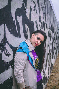 Portrait of woman standing against graffiti wall