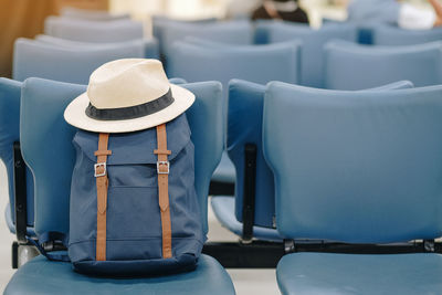 Hat and backpack on empty blue chair at airport