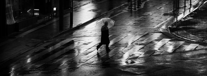 High angle view of man walking on wet street in city