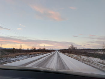 Road seen through car windshield during sunset