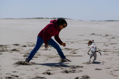 Woman playing with dog on beach