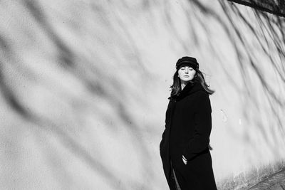 Young woman standing by wall