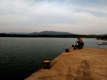People sitting on lake against sky