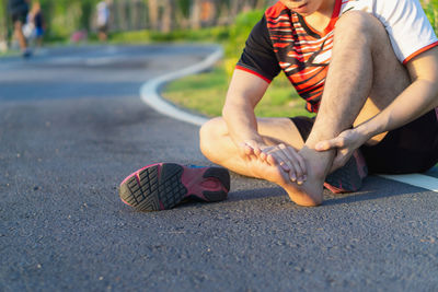 Low section of man skateboarding on road
