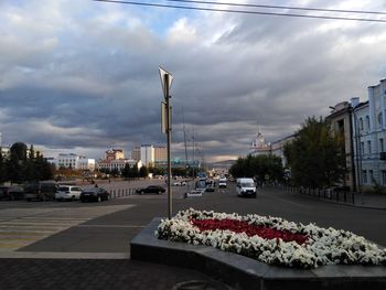 Cars on city street against sky