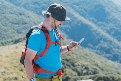 Midsection of man using mobile phone against mountain
