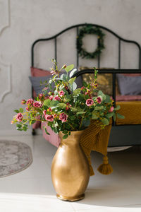 A luxurious bouquet of flowers in a floor-standing golden vase near the bed in the bedroom 