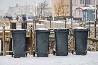 Grey garbage bins on street in winter. public trash containers on side of road. infectious control