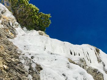 Low angle view of snowcapped mountain against blue sky