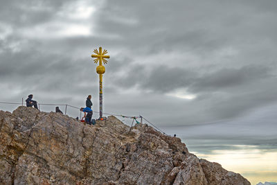 People on rock against sky