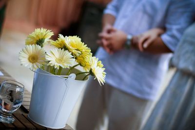 Close-up of yellow flowers in container against couple