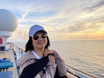 Portrait of smiling woman in sea against sky during sunset