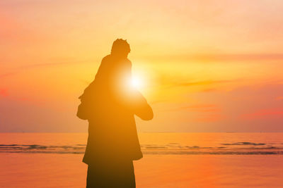 Silhouette man standing on beach during sunset