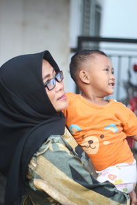 A woman with hijab and a boy looking away