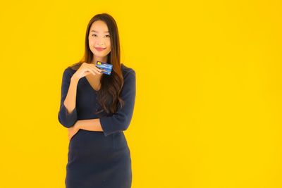 Portrait of a smiling young woman against yellow background