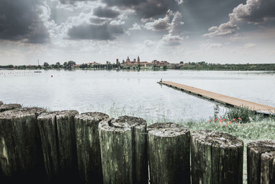 Panoramic shot of wooden posts in sea against sky