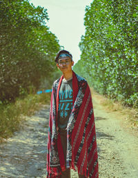 Portrait of young man standing on dirt road